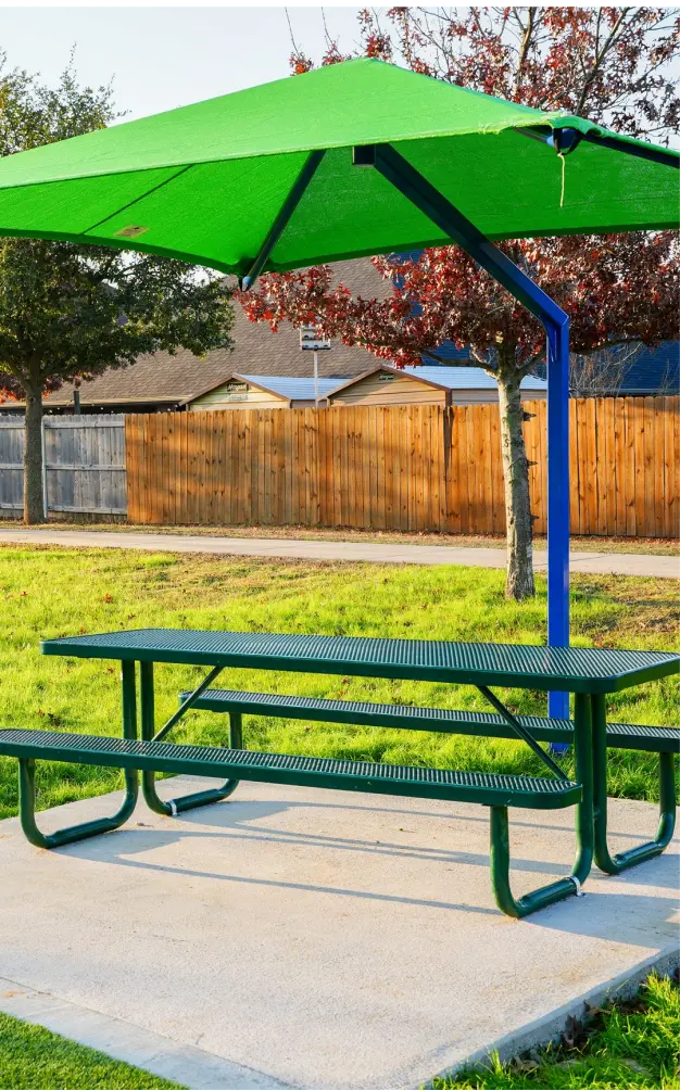 Outdoor park site furnishings featuring a durable commercial bench integrated with a protective overhead shade structure for sun-safe park seating areas